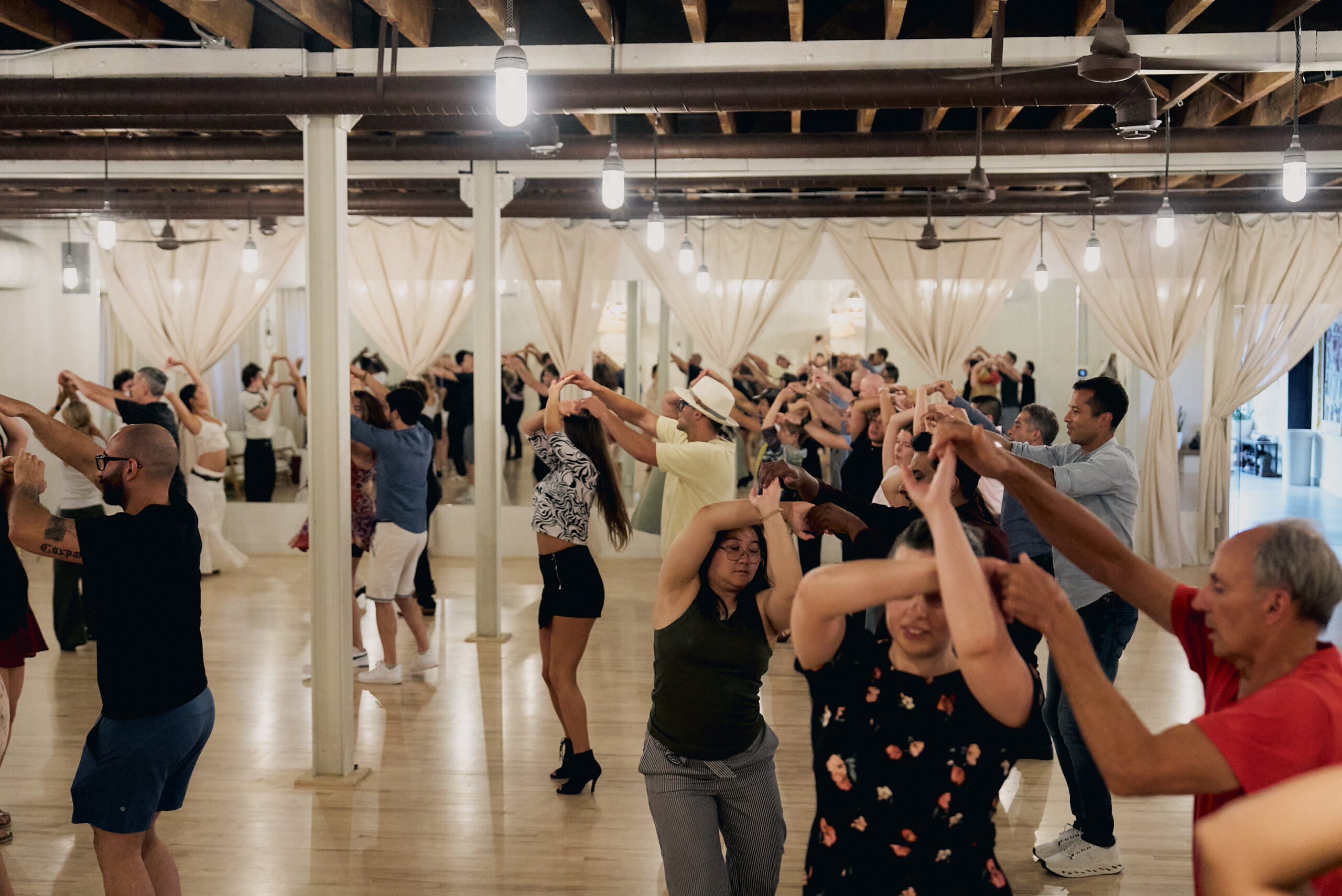 Full group dance class practicing a partner turn at Beach Ballroom studio in Toronto