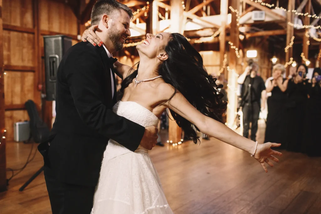 Bride laughing as the groom spins her during their wedding first dance